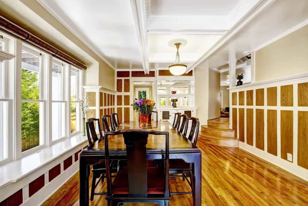 a dining room with wood trims, wooden floors and cabinets