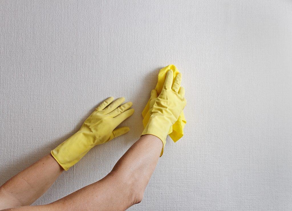 person with gloves cleaning the drywall thoroughly