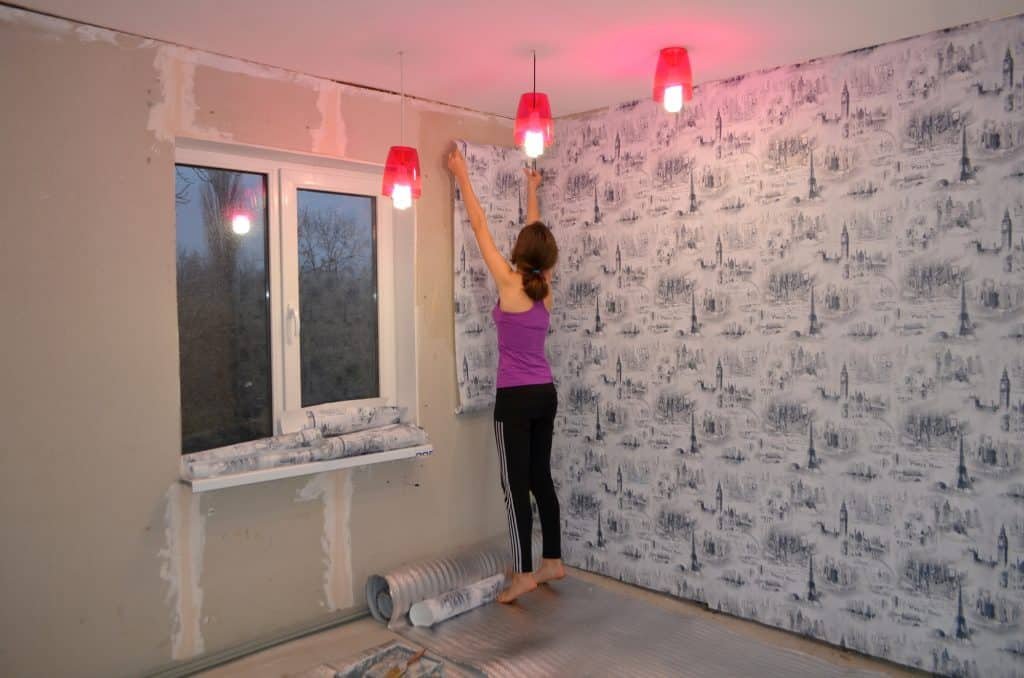 woman applying wallpaper to the drywall