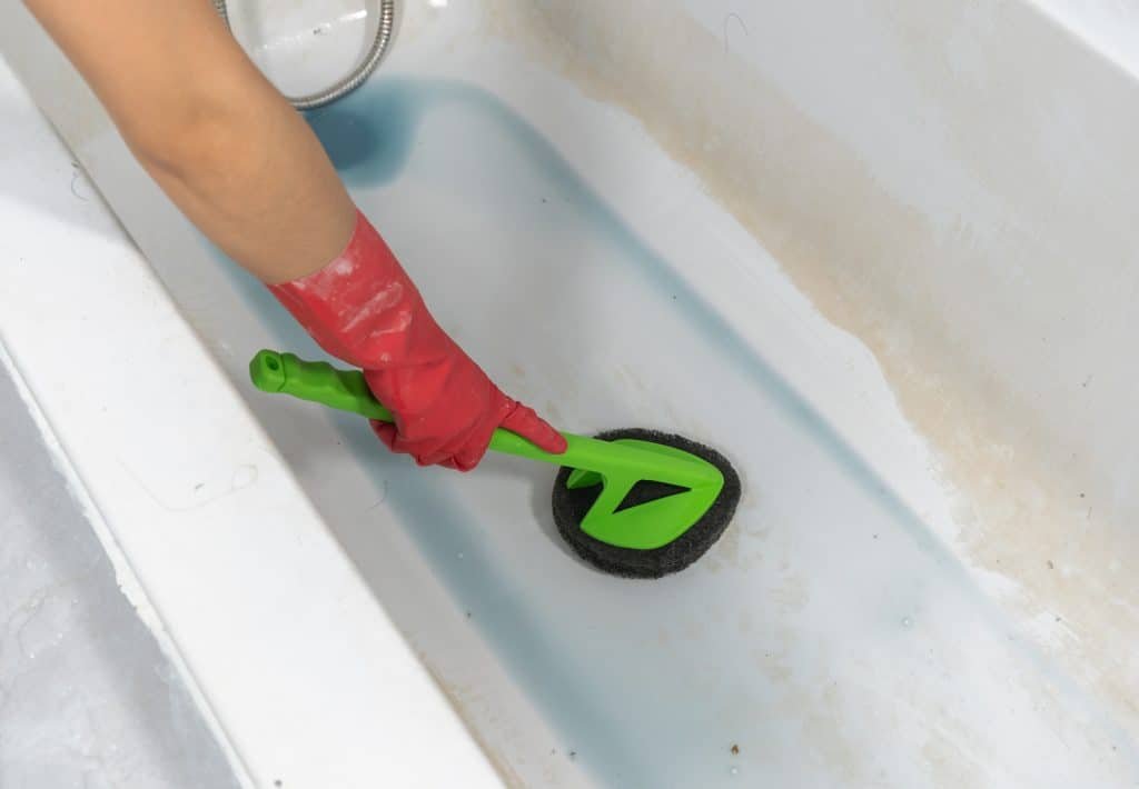 a person cleaning a jetted tub with a brush