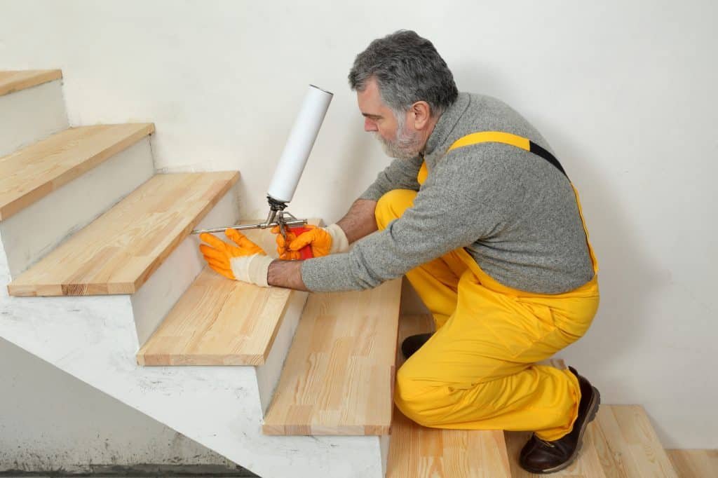 carpenter using polyurethane sealant spray to seal washable paint on wood
