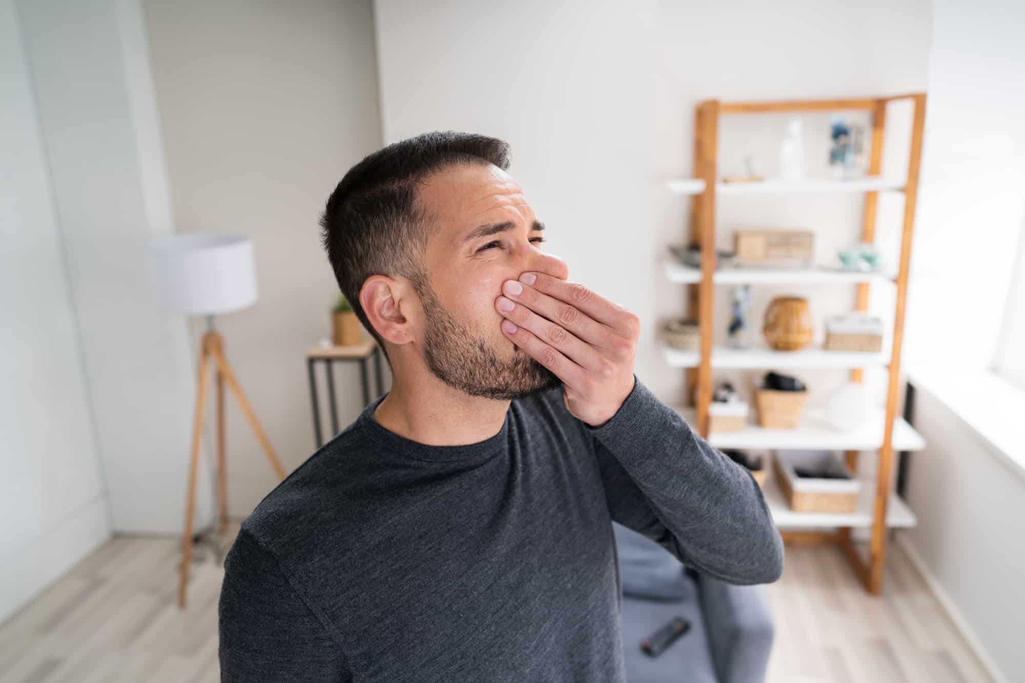 man covering his nose because his house smells of paint