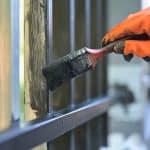 painting the steel gate using a paint brush