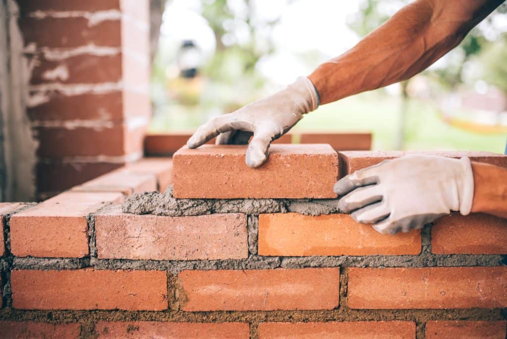 construction worker laying red clay bricks