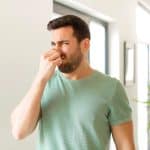 man covering his nose because of the car exhaust smell