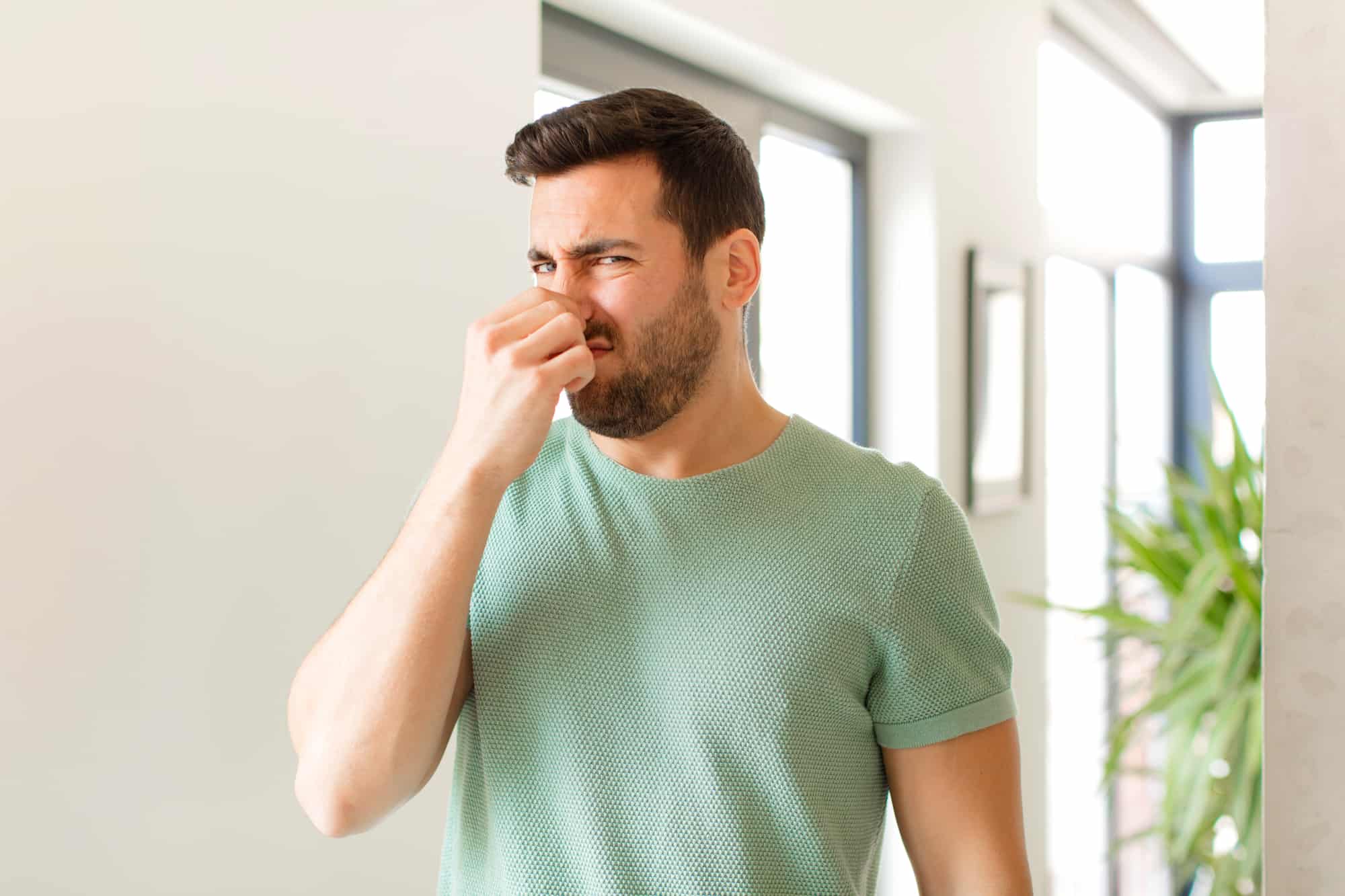 man covering his nose because of the car exhaust smell