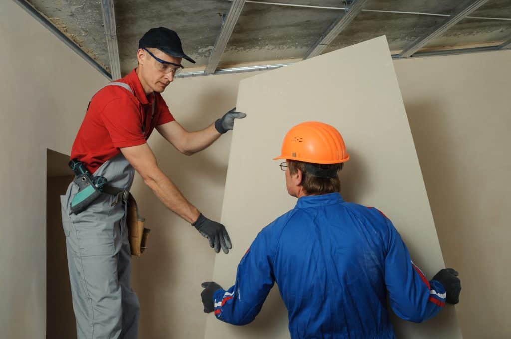 builders holding a drywall to install