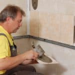 man tiling over painted drywall