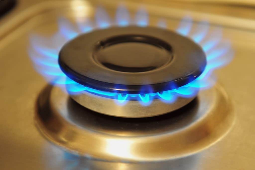 stainless steel gas burner turned on with blue gas flame