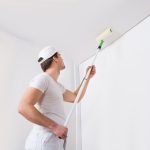 man painting a ceiling using a roller