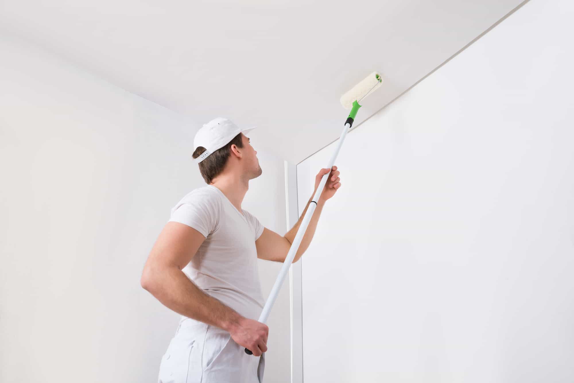 man painting a ceiling using a roller