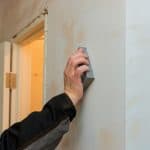 man using sand trowel sanding the drywall