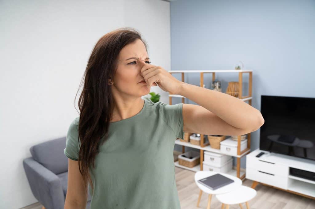 woman covering her nose because of sewer smell in the house