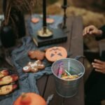 A Person Sitting at a Table with Halloween Decorations and a Bucket of Candies Tips for Halloween